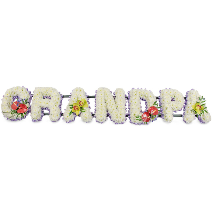 This carefully crafted funeral flower tribute forms the word "GRANDPA" in bold, horizontal lettering, displayed clearly against a clean white background so the structure and artistry stand out. Each capital letter is shaped from tightly packed, snow-white chrysanthemums or similar small blooms, arranged so closely that the flowers create a continuous, cushion-like surface with gentle ripples of texture. The uniform white suggests purity, remembrance, and a peaceful farewell. At the base of the letters, a fine trim of soft lavender ribbon peeks through, tracing a light purple edge that gives each character subtle definition without distracting from the calm white mass of petals. The letters rest along understated dark green bars that run beneath them, providing the support needed for use on a hearse, beside the coffin, or at a graveside service in Ickenham, perhaps near St Giles' Church or along Swakeleys Road. Carefully chosen accent sprays add both colour and sentiment: on the 'G' and 'D', deep red anthuriums with glossy, heart-shaped spathes and prominent spadices are nestled among rich green foliage and tiny touches of purple, bringing warmth and intensity. On the first 'A' and the final 'A', clusters of yellow-green orchids introduce a touch of refined elegance, their arching petals and fresh greenery softening the design with a sense of continuing life and quiet dignity. This "GRANDPA" floral lettering is the type of bespoke memorial tribute often requested from experienced local florists in Ickenham, created to accompany a funeral, cremation, or graveside gathering and to express love, gratitude, and respect for a much-missed grandfather.